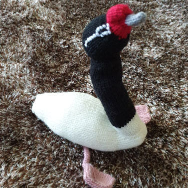 Knitted swan toy on a brown textured surface
