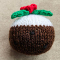 Knitted Christmas pudding with a cherry on top on a beige background
