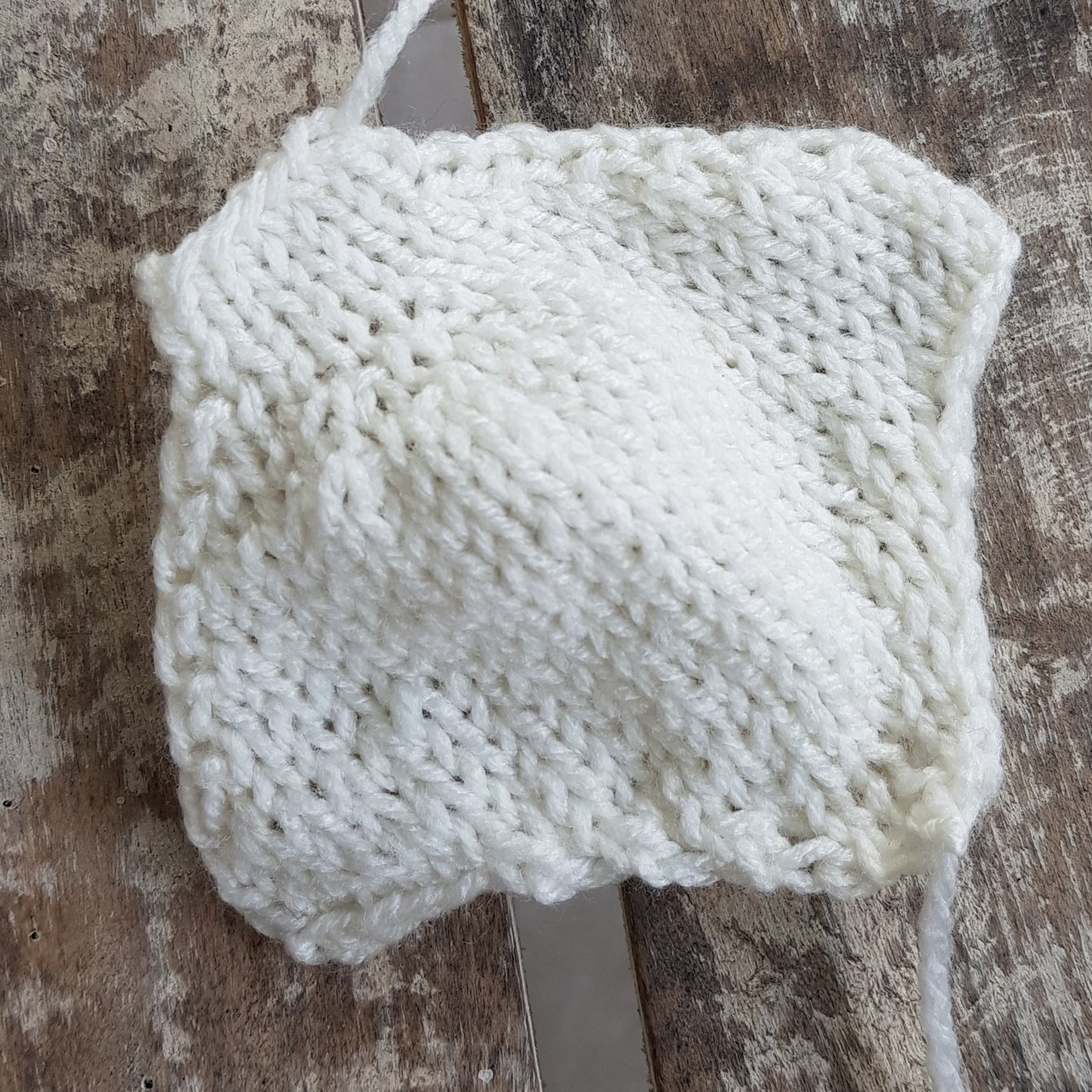 Close-up of a partially completed knitted manta ray underside body in cream yarn.