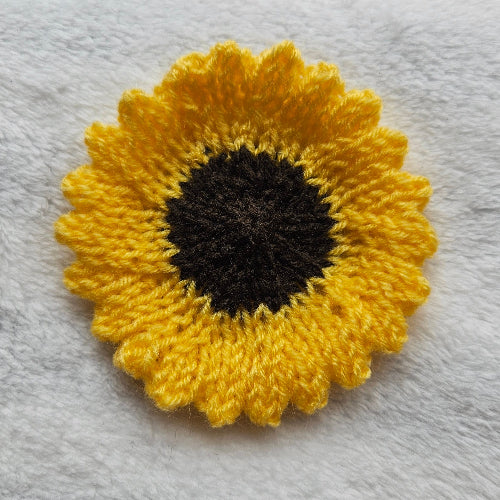 Knitted sunflower coaster on a textured gray surface