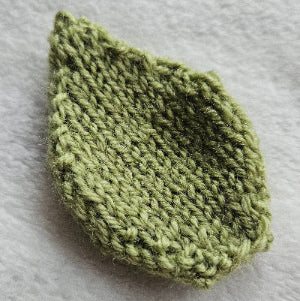 Knitted green leaf-shaped fabric on a gray background