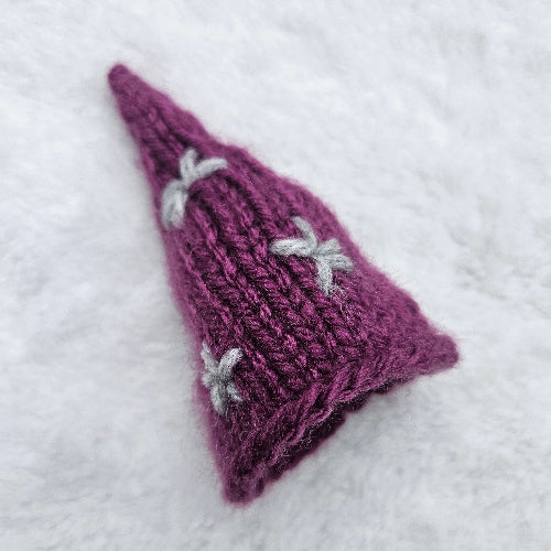 Purple knitted triangle with white patterns on a white background