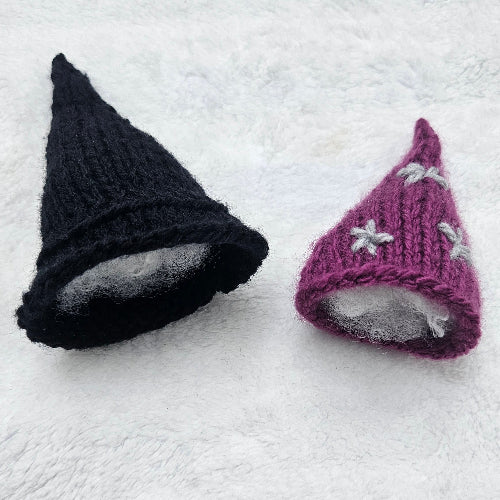 Purple and black knitted hats on a white textured surface