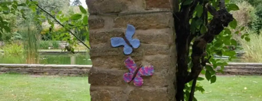 Butterfly-shaped decorations on a stone wall with a garden background