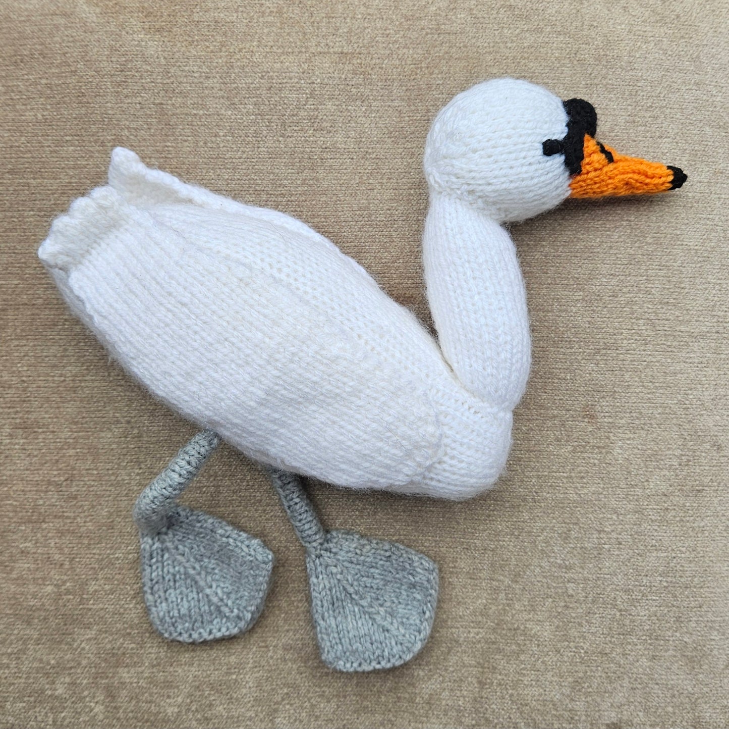 Knitted swan toy on a beige surface