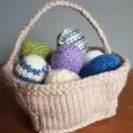 Woven basket with yarn eggs inside on a wooden surface