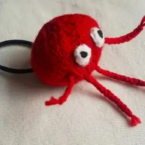 Red knitted nose toy with black eyes on a beige background