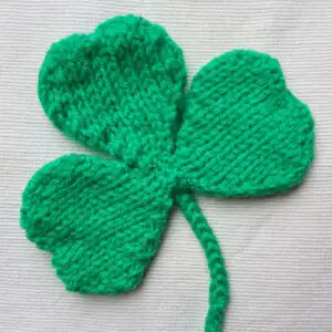 Knitted green four-leaf clover on a light background