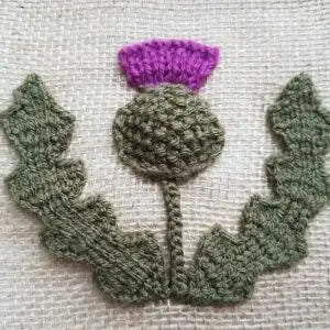 Knitted thistle with purple top on a textured background