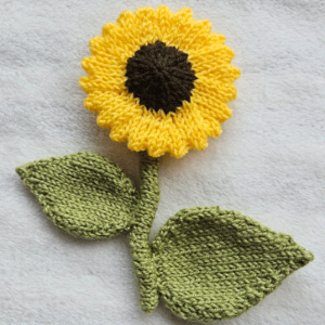Knitted sunflower with green leaves on a gray background