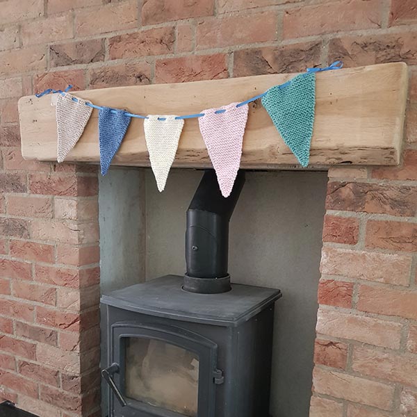 Knitted bunting triangles in mixed colours strung across a mantel.