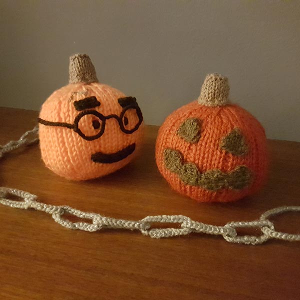 Knitted pumpkins with stem and chain, styled for Halloween display.