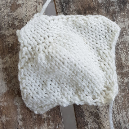 Close-up of a partially completed knitted manta ray underside body in cream yarn.