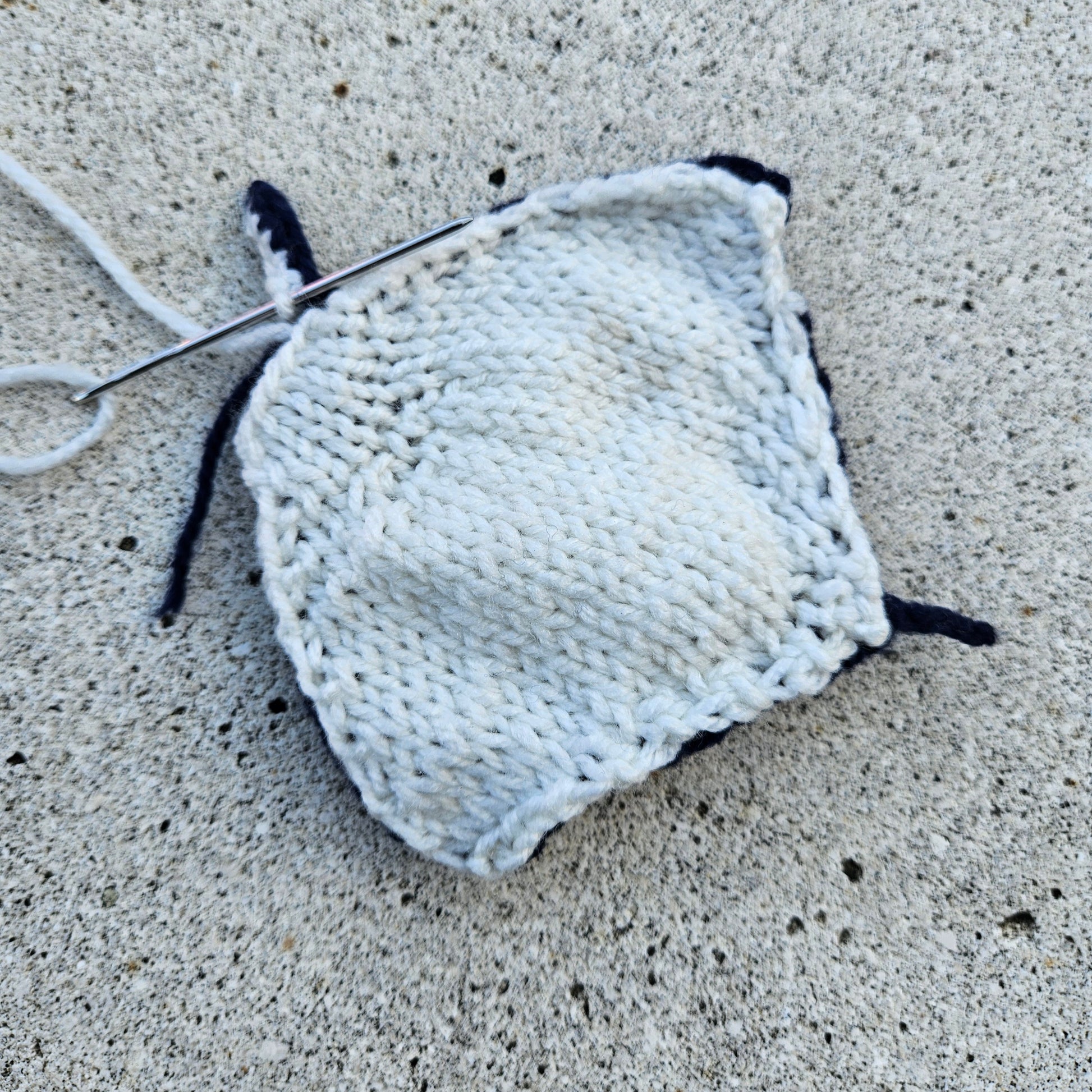 In-progress sewing of a knitted manta ray, showing the stuffing and yarn stitching.