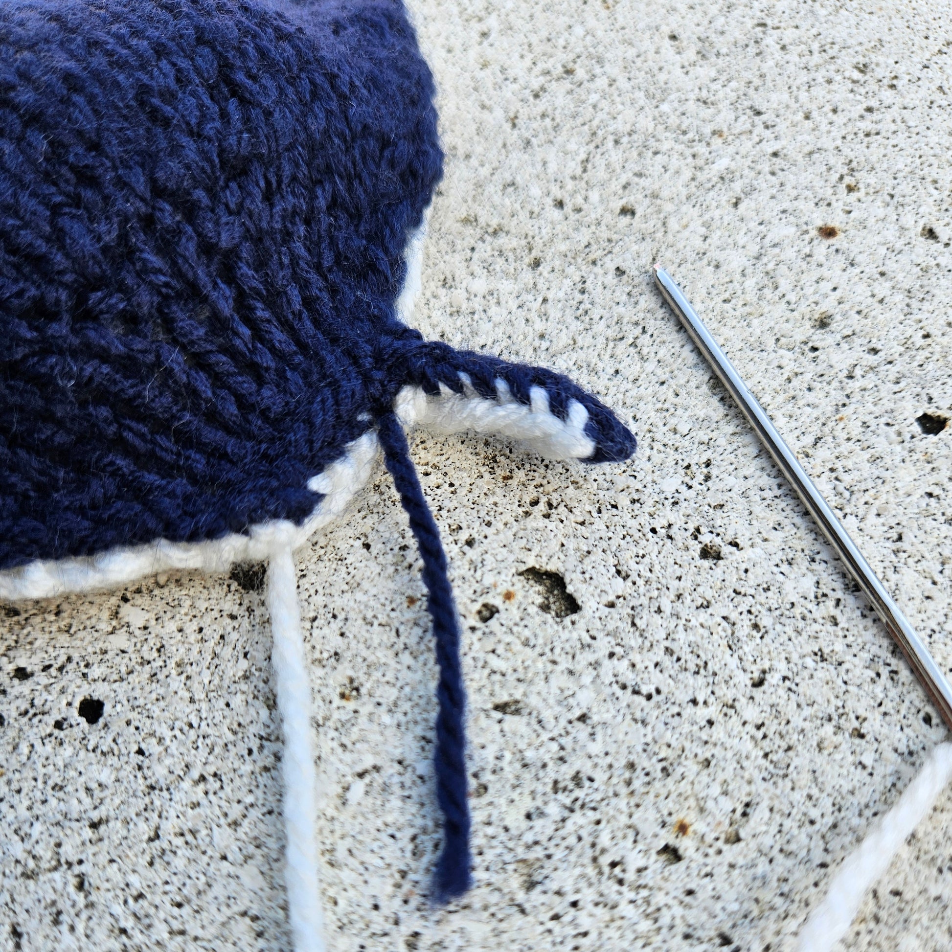 Detail of a knitted manta ray mouth being sewn, showing needlework in progress.