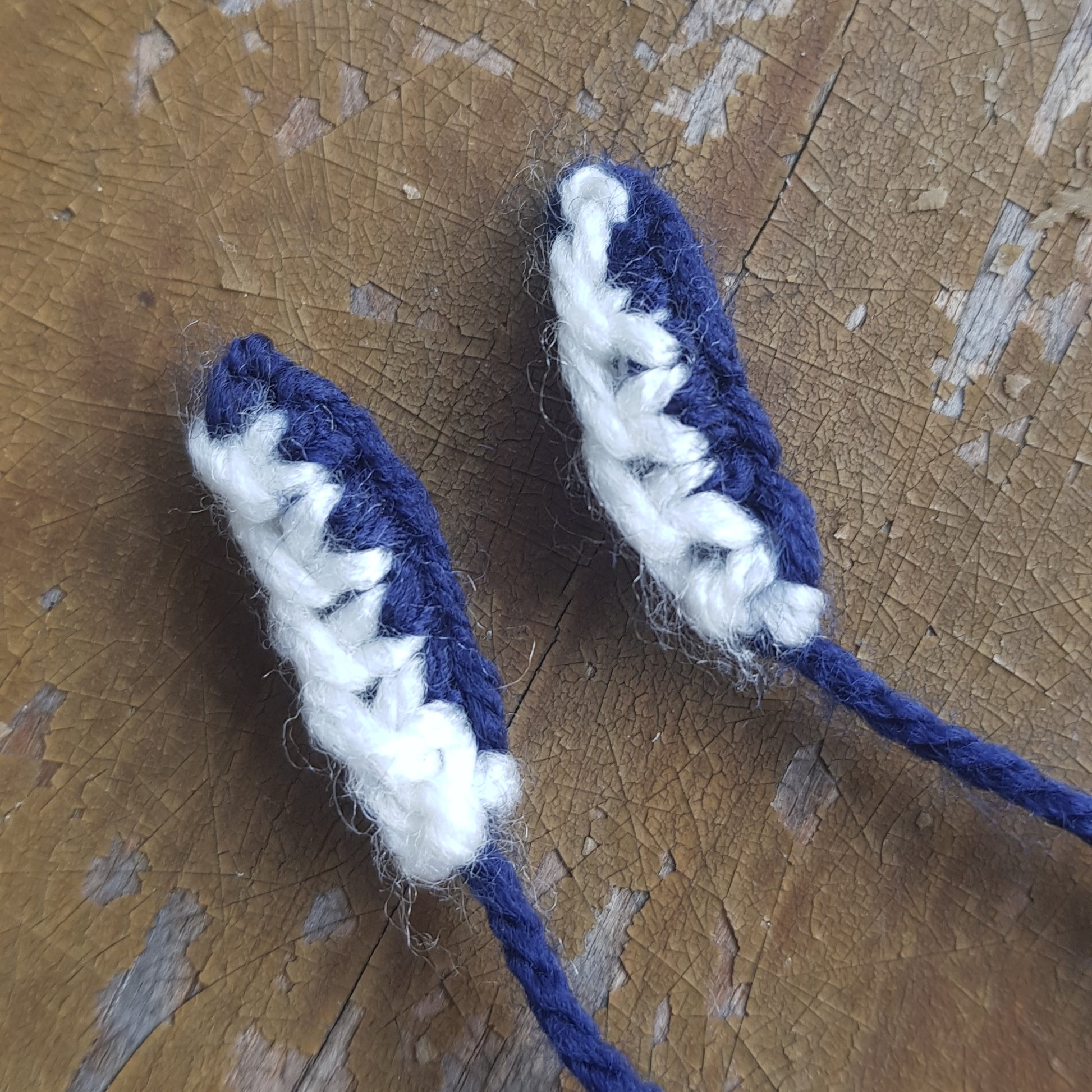 Close-up of completed knitted manta ray mouthpieces made with white and dark blue yarn.