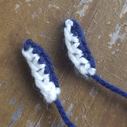 Close-up of completed knitted manta ray mouthpieces made with white and dark blue yarn.