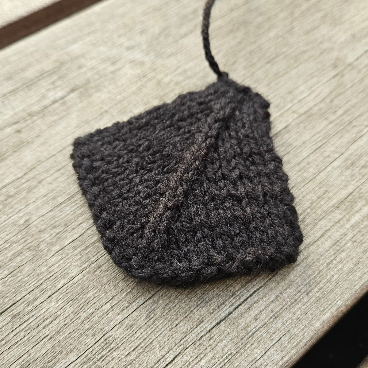 Black knitted webbed swan foot laid flat on a wooden surface.