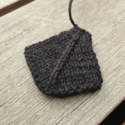 Black knitted webbed swan foot laid flat on a wooden surface.