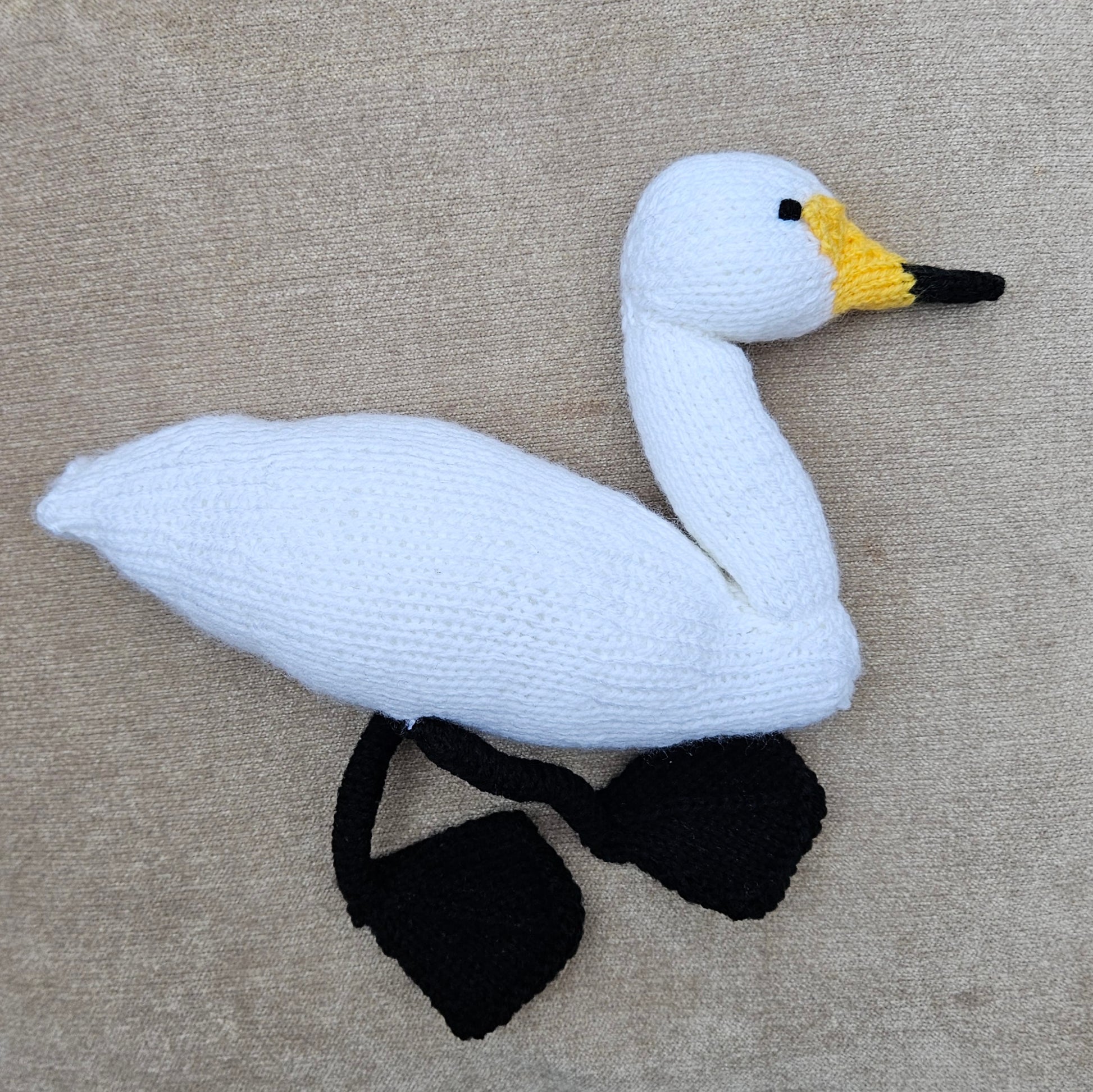 Knitted swan toy on a beige fabric background
