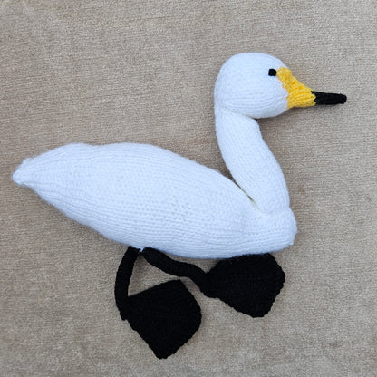 Knitted swan toy on a beige fabric background