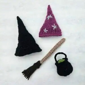 Knitted witch hat, broomstick, and bag on a white background