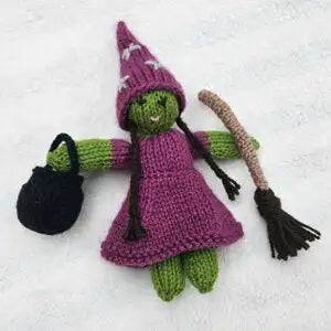 Knitted witch doll with a broom and black bag on a white background